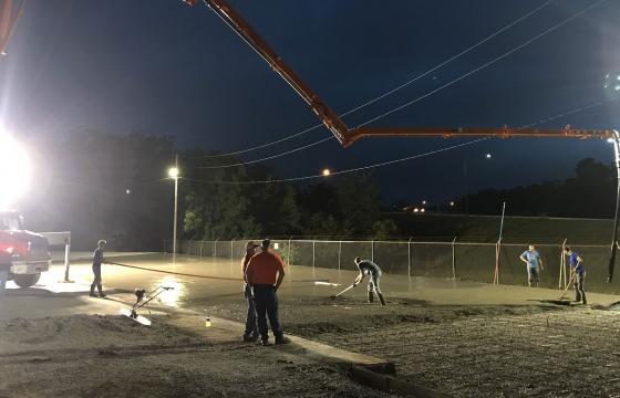 Night time construction team pouring concrete for a parking lot